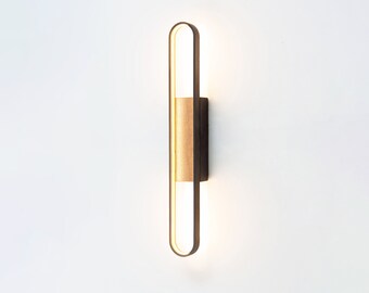 Puede incluir: Una lámpara de pared moderna con un marco de metal negro y un acento de madera. La luminaria tiene una fuente de luz LED blanco cálido.
