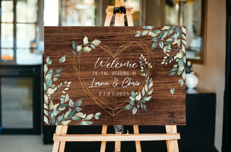 May include: Welcome to the wedding of Lorna & Chris, a rustic wooden sign with a gold geometric heart and green watercolor foliage.