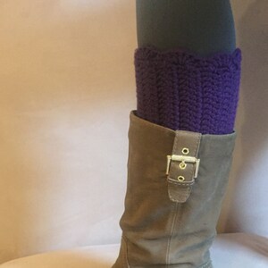 May include: Purple knitted leg warmers worn over brown suede boots with a gold buckle.