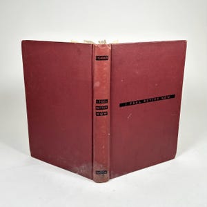 May include: An open book with a burgundy cover and spine. The spine features the title "I Feel Better Now" and the author's name, "Fishback." The book's cover also displays the title in a black, horizontal font. The book is set against a white background.