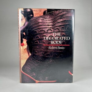 May include: The cover of a book titled "The Decorated Body" by Robert Brain. The cover features a close-up of a person's back covered in intricate patterns of small, raised dots.