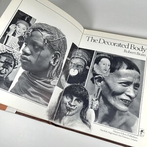 May include: A book titled "The Decorated Body" by Robert Brain. The cover features black and white photographs of people from different cultures with various forms of body decoration, including facial markings, jewelry, and elaborate hairstyles.