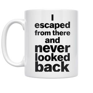 May include: White ceramic mug with a curved handle. The mug features the black text: "I escaped from there and never looked back."