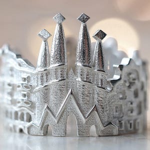 Könnte beinhalten: Silberring mit einem detaillierten Design einer Stadtlandschaft, mit mehreren Gebäuden mit spitzen Dächern.