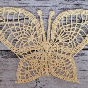 Puede incluir: Una delicada mariposa de ganchillo en color amarillo p&aacute;lido. La mariposa tiene detalles intrincados y un dise&ntilde;o de encaje.