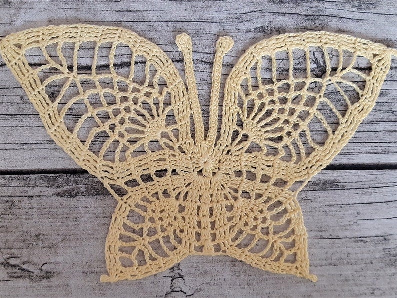 Puede incluir: Una delicada mariposa de ganchillo en color amarillo p&aacute;lido. La mariposa tiene detalles intrincados y un dise&ntilde;o de encaje.