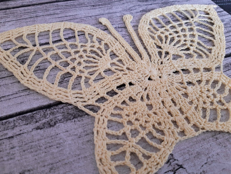 Puede incluir: Una delicada mariposa de ganchillo en color crema. La mariposa est&aacute; hecha con un hilo fino y tiene un delicado patr&oacute;n de encaje.