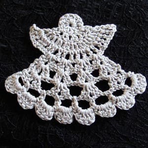 Puede incluir: Un adorno de &aacute;ngel de crochet blanco con un dise&ntilde;o delicado. El adorno est&aacute; hecho de hilo fino y tiene un aspecto de encaje.