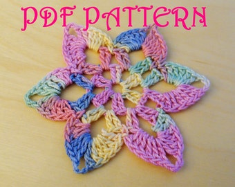 Puede incluir: Una flor de crochet colorida con un esquema de colores pastel, que incluye rosa, azul, amarillo y verde. La flor tiene seis puntas y está hecha con un delicado patrón de puntadas. La imagen incluye el texto "PDF PATTERN".
