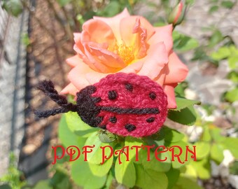 May include: A crocheted ladybug with black legs and red and black spots, sitting on a pink rose.