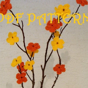Könnte beinhalten: Ein PDF-Muster zum Häkeln eines Zweigs mit orangefarbenen und gelben Blüten. Die Blüten sind in einem einfachen, vierblättrigen Design gehäkelt.