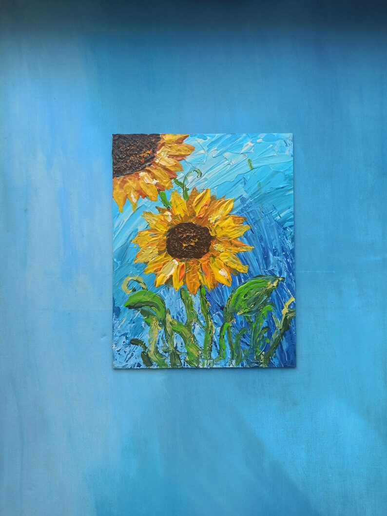 K&ouml;nnte beinhalten: Ein Gem&auml;lde von zwei Sonnenblumen auf blauem Hintergrund. Die Sonnenblumen sind realistisch gemalt mit gelben Bl&uuml;tenbl&auml;ttern und braunen Zentren. Der Hintergrund ist hellblau mit Pinselstrichen.