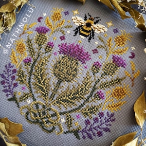Symmetrical floral garden cross stitch pattern featuring a bumblebee and elegant botanical ornaments in sampler style.
