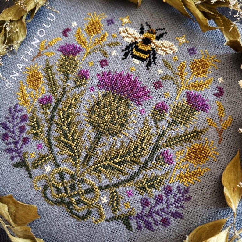 Symmetrical floral garden cross stitch pattern featuring a bumblebee and elegant botanical ornaments in sampler style.