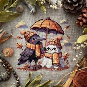 Könnte beinhalten: Kreuzstich-Kunstwerk mit einer Krähe und einem weißen Wesen unter einem orangefarbenen Regenschirm. Beide tragen passende Mützen und Schals. Die Szene spielt im Herbst mit fallenden Blättern und einem neutralen Hintergrund. Der Künstlername, @NATHNOLU, ist sichtbar.