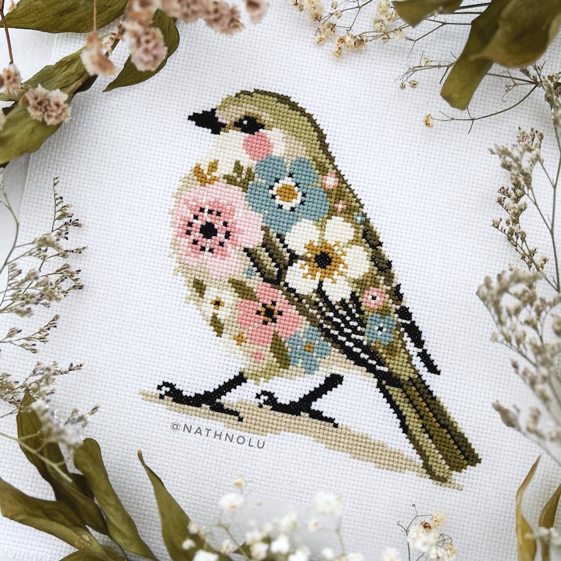 Cross stitch pattern of a tiny spring bird with floral details in soft pastel colors, perfect for cottagecore decor