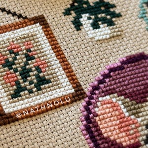 Cozy farmhouse decor cross stitch featuring a tiny mouse enjoying crochet in a warm armchair corner
