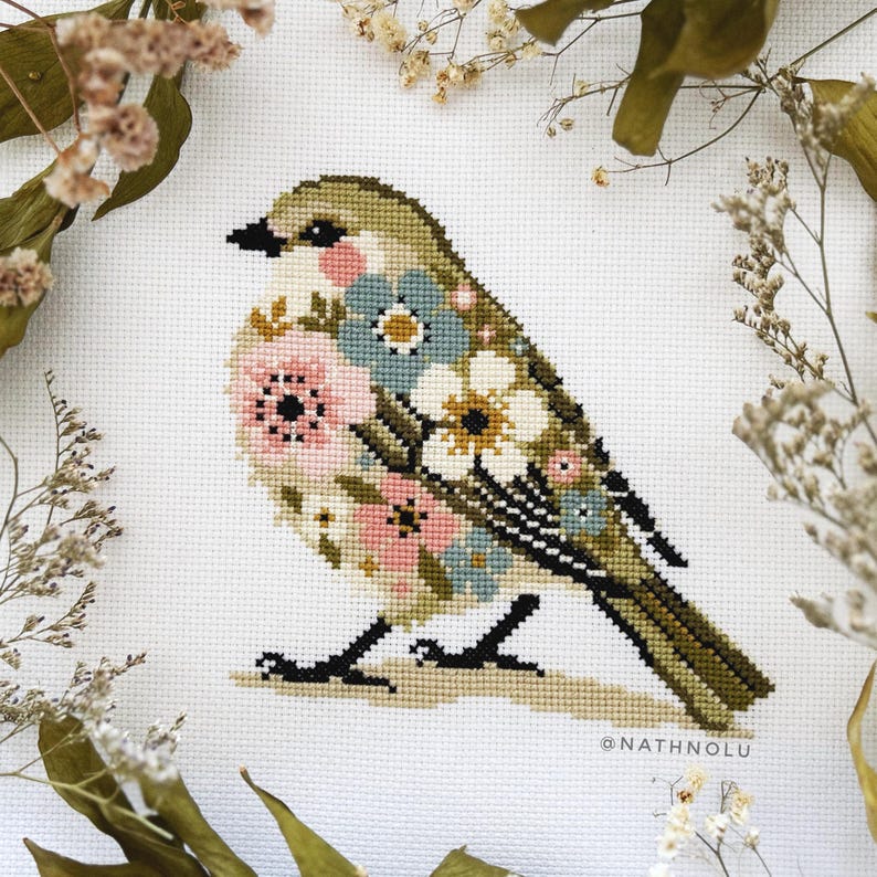 Cozy little bird cross stitch with delicate flowers on its body, a charming addition to any woodland animal embroidery collection