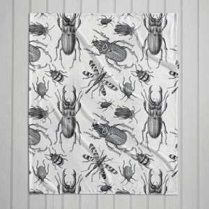 May include: A white fabric with a black and white repeating pattern of various beetle illustrations. The beetles are drawn in a vintage style.