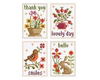 May include: Four cross-stitch patterns with floral and animal motifs. The patterns include a basket of flowers with the text "thank you", a potted plant with the text "lovely day", a bird on a branch with the text "smiles", and a rabbit with the text "hello".