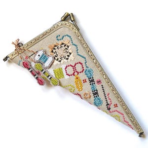 Può includere: Un astuccio triangolare beige a punto ago con una cornice in metallo color oro. L'astuccio è decorato con immagini a punto croce di strumenti di cucito, tra cui forbici, rocchetti di filo e aghi. L'astuccio è lungo circa 20 cm.