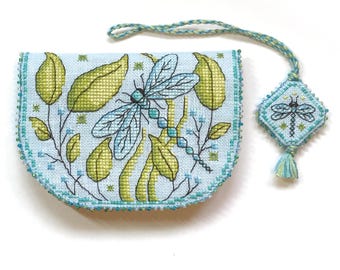 May include: A blue and green needlepoint pouch with a dragonfly design and a matching tassel charm. The pouch is decorated with a beaded border.