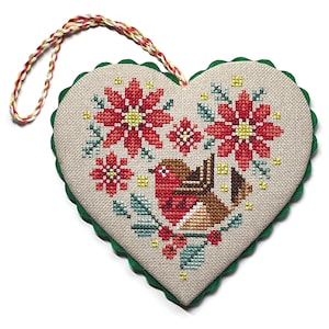 Pode incluir: Enfeite em ponto cruz em forma de coração com um pisco-de-peito-ruivo e poinsétias. O enfeite tem uma borda verde ondulada e um cordão de suspensão multicolorido. O design inclui detalhes em ponto cruz vermelho, castanho, verde e amarelo sobre um fundo bege.
