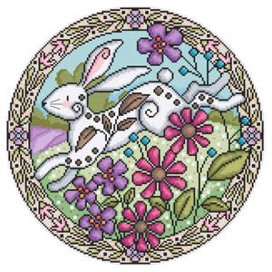 Può includere: Un coniglio bianco con macchie marroni e un disegno floreale corre attraverso un campo di fiori colorati. Il coniglio è circondato da una cornice circolare con un disegno floreale.