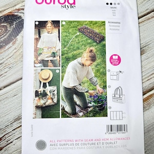 Op de afbeelding: Een Burda Style naaipatroonpakket, nummer 5909, met afbeeldingen van accessoires en een vrouw die de genaaide items draagt. Het pakket heeft de tekst "ALL PATTERNS WITH SEAM AND HEM ALLOWANCES".