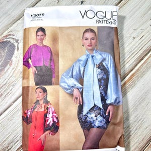 Può includere: Modello Vogue V2079. Il modello presenta immagini di donne che indossano vari outfit, tra cui una giacca rosa, un top blu con fiocco e una giacca floreale. La gamma di taglie del modello è da XS a XL.