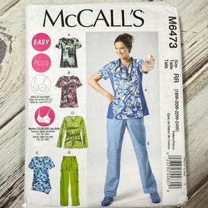 May include: McCall's sewing pattern M6473. The pattern includes designs for scrubs, tops, and trousers. The cover features a woman wearing a blue floral scrub top and trousers. Sizes available are 18W-24W.