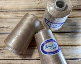 1 spole pergamentbrun kraftig bomullsquilttråd 2500 M, 40 Wt. Märke Threadart. Merceriserad 100 % bomullstråd. Quilttråd.