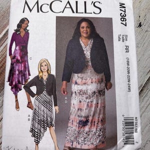 May include: A sewing pattern for a dress and jacket. The pattern is for sizes 18W-20W-22W-24W. The dress has a black and white striped pattern and the jacket is black. The pattern is from McCall's and the model name is Khalihah Ali.