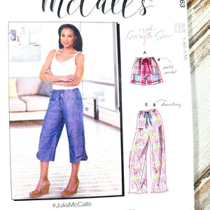 Op de afbeelding: McCall's naaipatroon M8063. Het patroon bevat instructies voor het maken van culottes en broeken. De omslag toont een vrouw die een blauwe culotte draagt. De tekst op het patroon luidt "Learn to Sew" en "#JuliaMcCalls".