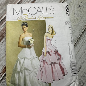 Może przedstawiać: Wzór szycia McCall's Bridal Elegance do sukni ślubnej. Wzór jest dla rozmiarów 14-16-18-20. Wzór pokazuje dwa różne style sukni ślubnych, jedną z gorsetem bez ramiączek i pełną spódnicą, a drugą z gorsetem bez ramiączek i spódnicą warstwową.