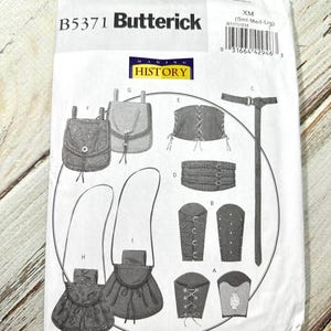 Peut inclure: Un patron de couture Butterick, B5371, avec des illustrations d'accessoires de costumes historiques. Le paquet comprend des schémas de sacs, de manchettes et d'autres articles. Le texte "MAKING HISTORY" est également visible.