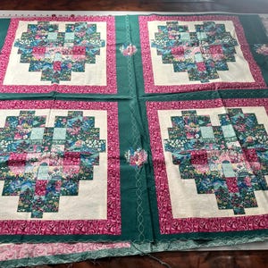 May include: Four fabric squares with a green border and a pink inner border. Each square features a white background with a patchwork heart design in shades of blue, green, and pink.