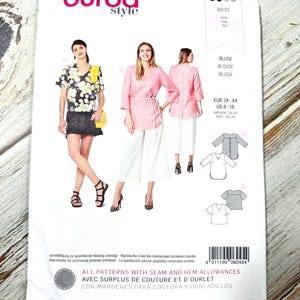 Pode incluir: Um pacote de padrões de papel branco com o logótipo Burda Style. O pacote mostra imagens de mulheres a usar blusas. O texto inclui "BLUSE", "BLOUSE", "BLUSA" e informações sobre tamanhos. O pacote também indica "ALL PATTERNS WITH SEAM AND HEM ALLOWANCES".