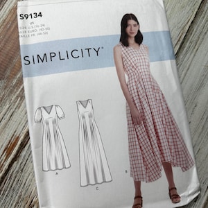 May include: A sewing pattern for a dress with three different styles. The pattern is for sizes US 16-24, Euro 42-50, and French 44-52. The pattern is called Simplicity S9134.