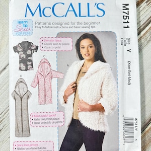 May include: A McCall's sewing pattern for a hooded jacket, size Y (Xsm-Sml-Med). The pattern features a woman wearing a white faux fur jacket. The pattern includes instructions for sewing with fleece, making a patch pocket, and sewing a lined garment.