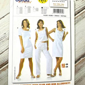 Op de afbeelding: Een Burda Easy naaipatroonpakket met drie witte jurk- en broekpakontwerpen. Het pakket bevat afbeeldingen van de afgewerkte kledingstukken en tekst in meerdere talen, waaronder "Dress" en "Vestido."