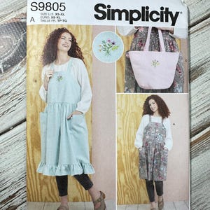 以下が含まれることがあります： SimplicityのソーイングパターンS9805。エプロンとトートバッグが特徴です。ポケットとフリル付き裾のエプロンと、花の刺繍が施されたトートバッグの複数のビューが含まれています。パターンは米国で設計および印刷されています。