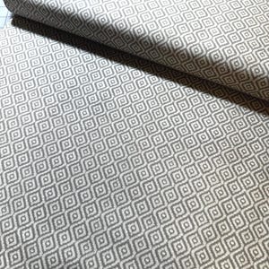 May include: A roll of fabric with a repeating geometric pattern of gray diamonds on a white background. The fabric is folded over, showing the pattern in detail. The fabric appears to be a medium weight, suitable for upholstery or home decor projects.