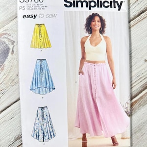 May include: Simplicity sewing pattern S9786 for skirts. The pattern includes illustrations of three skirt designs: yellow, blue, and floral. The package also features a photo of a woman wearing a pink skirt. The text "easy-to-sew" is visible.