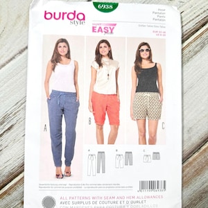 May include: A Burda Style sewing pattern packet, featuring three different pant styles: pants, shorts, and capris. The packet has the number 6938 in a green box. The models are wearing the finished garments. The packet includes seam and hem allowances.