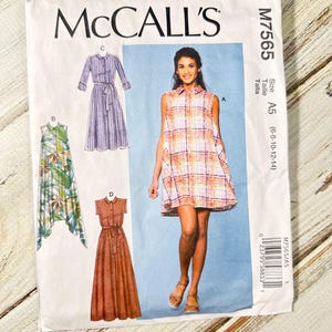 May include: McCall's M7565 sewing pattern featuring dress designs. The pattern includes illustrations of various dress styles, including a collared dress with a belt, a sleeveless dress, and a long dress with a belt. The pattern size is A5 (6-8-10-12-14).