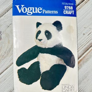 Può includere: Un modello di cucito vintage Vogue Patterns con un design di orso panda. La copertina è bianca con un banner blu in alto, che mostra il logo Vogue Patterns e i dettagli del modello. L'illustrazione del panda è in bianco e nero.