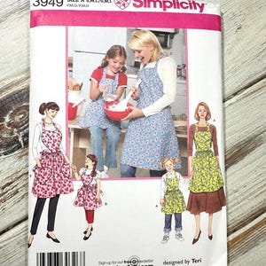 May include: Simplicity sewing pattern with apron designs. The pattern includes sizes A, S, M, and L. The cover shows illustrations of aprons with floral and fruit patterns. The pattern is designed by Teri.