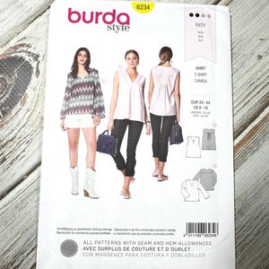 May include: A Burda Style sewing pattern packet, featuring three women modeling shirt designs. The packet is white with the Burda Style logo and the number 6234. Text includes "Shirt, T-Shirt, Camisa" and size information.