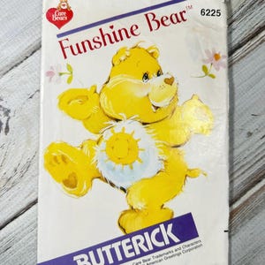 Peut inclure: Un patron Butterick vintage avec Funshine Bear de la série Care Bears. La couverture présente un ours jaune avec un emblème de soleil sur le ventre. Le design comprend le logo Care Bears et le numéro 6225.